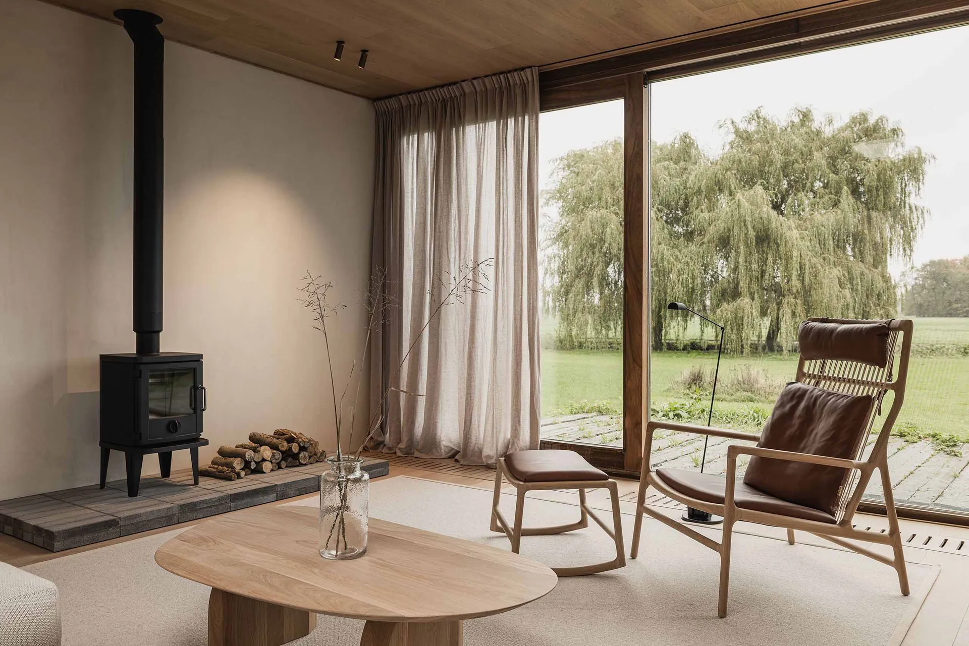 Contemporary minimalist living room featuring wood finishes, a floor-to-ceiling window overlooking greenery, a sleek coffee t