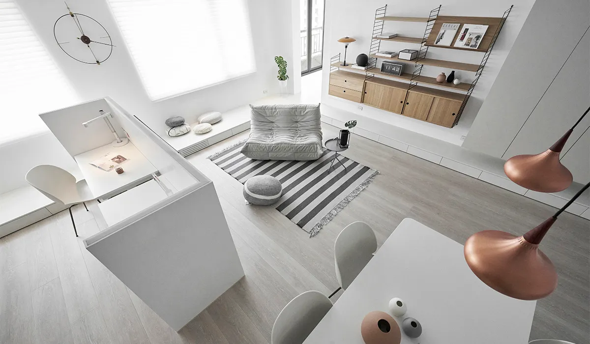 A modern minimalist living room with a white interior, featuring white furniture, a gray sofa, and a striped rug, with a copp