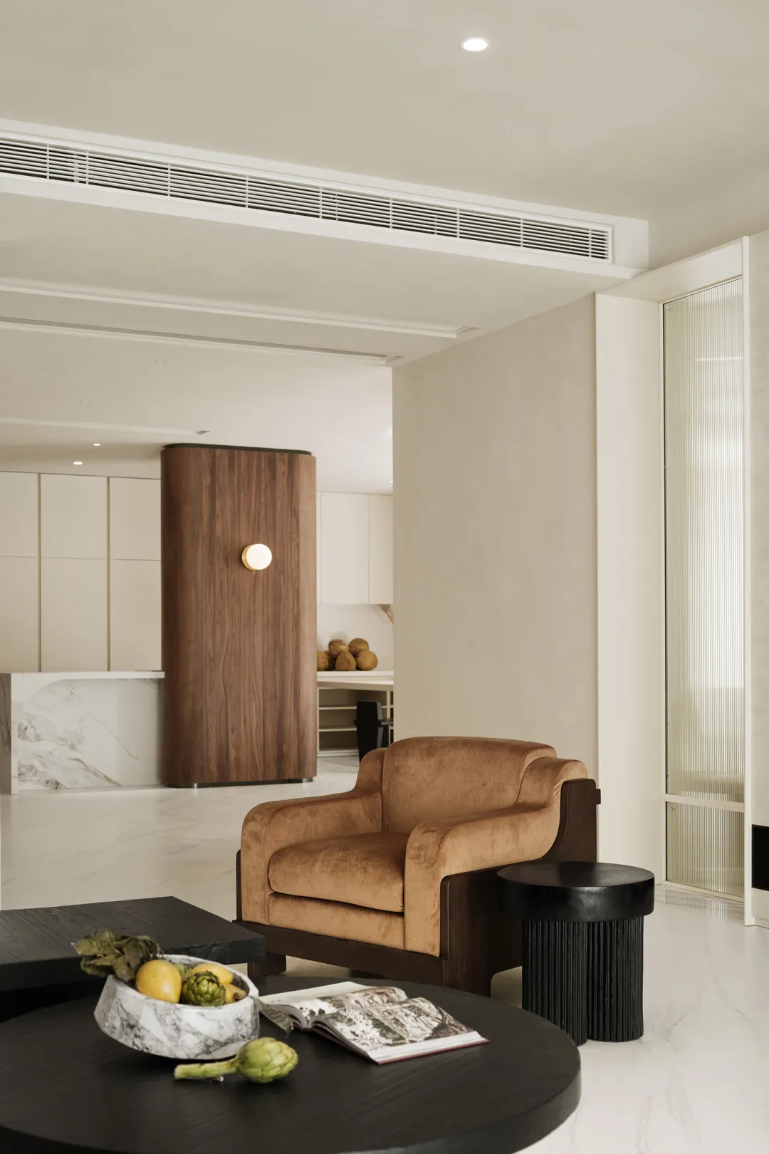 A modern living room with a sand brown leather couch, black round coffee table, and minimalist decor.