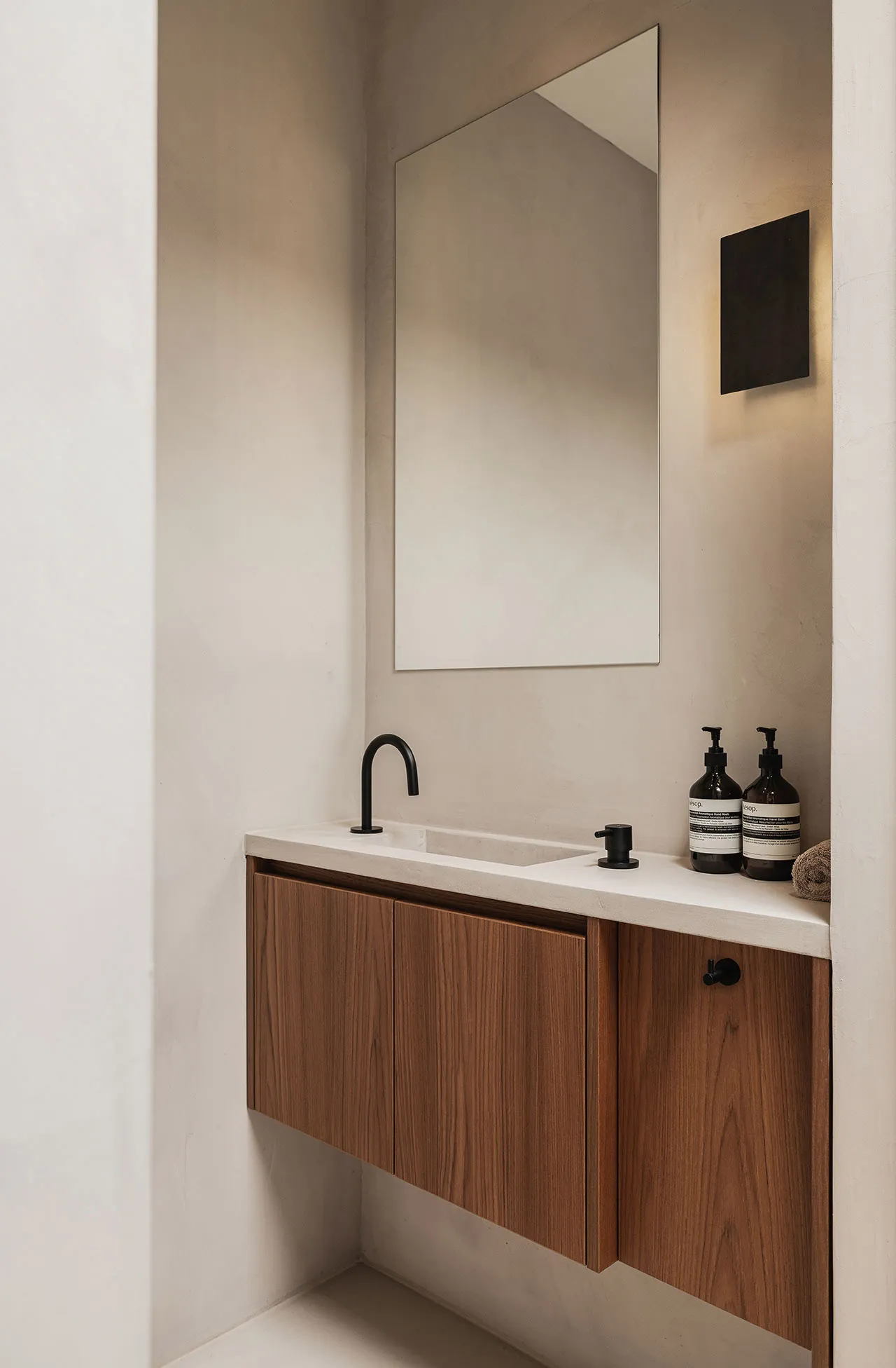 Sunlit modern bathroom with concrete sink, wooden cabinets, and a minimalist design.