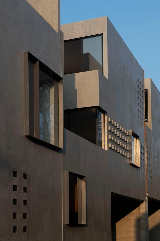 Concrete building exterior with geometric windows and vertical lines.