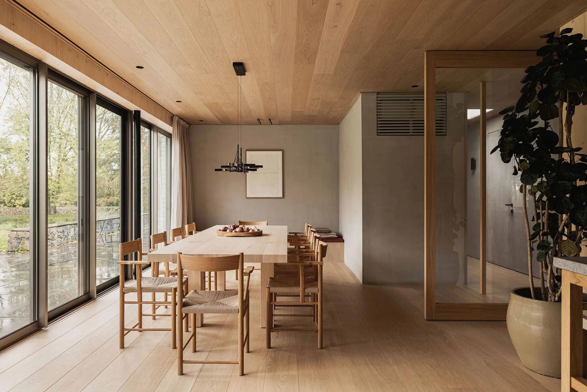 Modern living room featuring wooden furniture and large windows with a view of the outdoors.