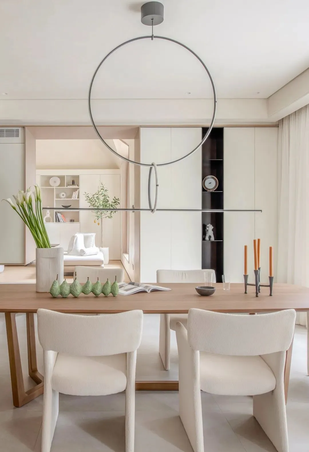 Modern minimalist dining room featuring white fabric chairs and a wooden dining table.
