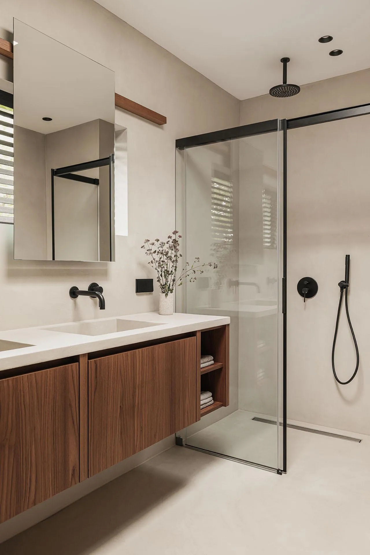 Modern bathroom featuring glass shower enclosure, wooden vanity, and minimalist decor.