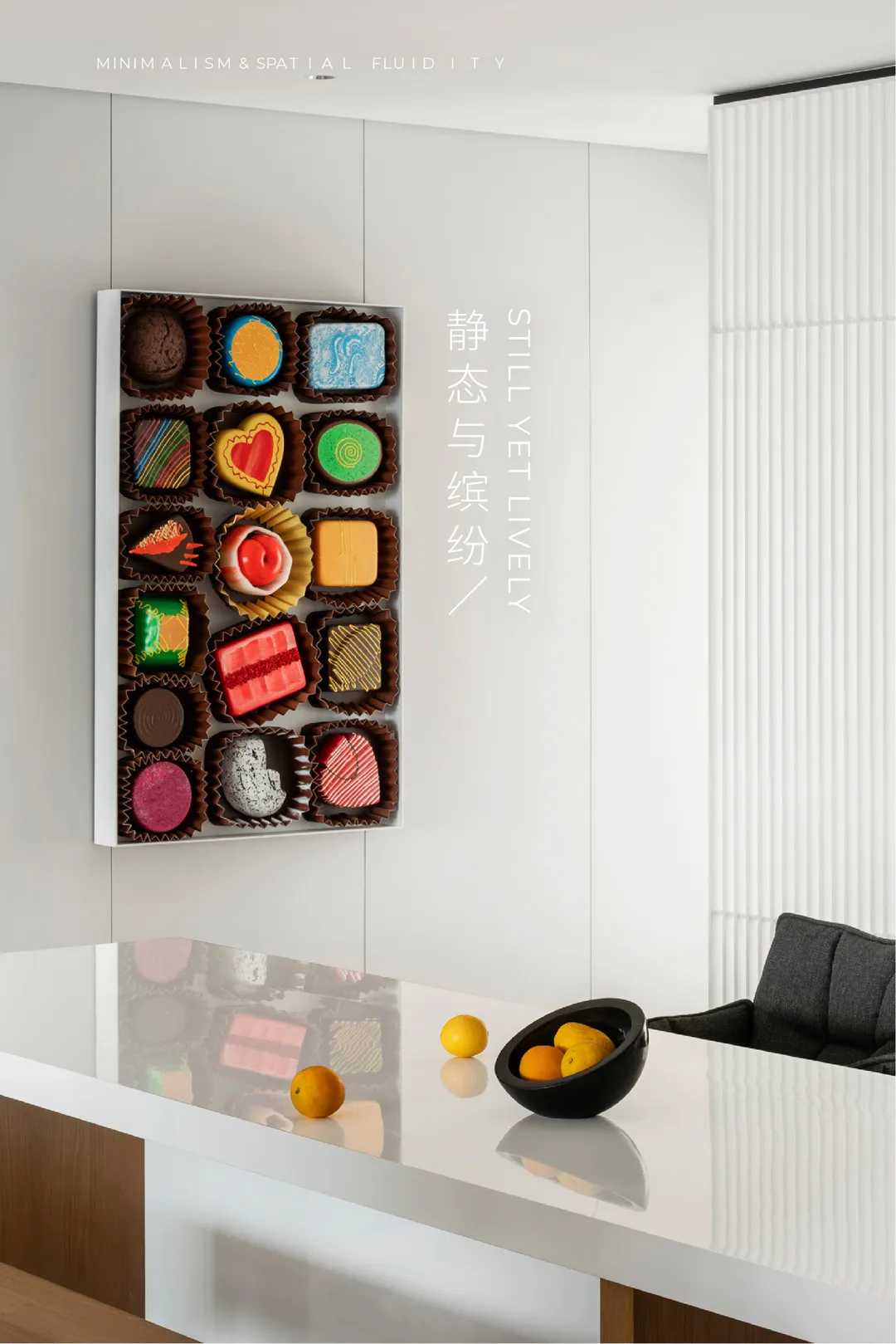 A well-designed minimalist interior featuring a sleek black table with oranges, a white counter with a black bowl of oranges,