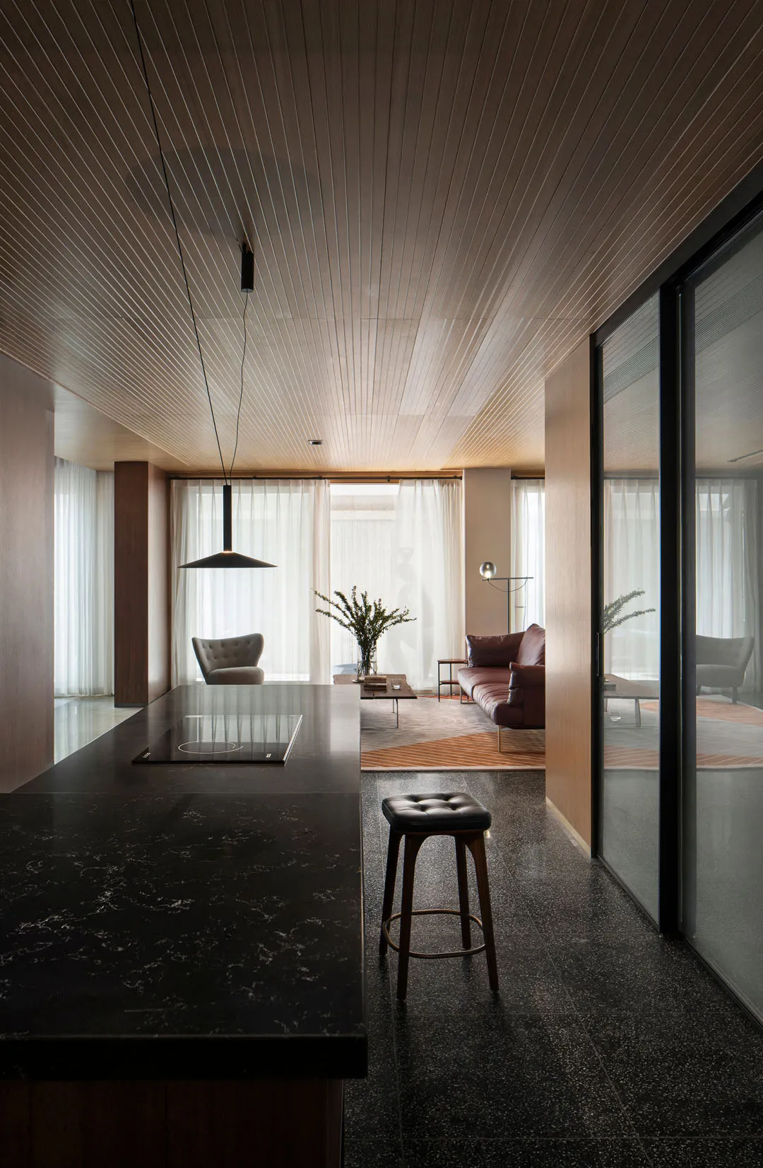A modern kitchen with a granite floor and wooden ceiling.