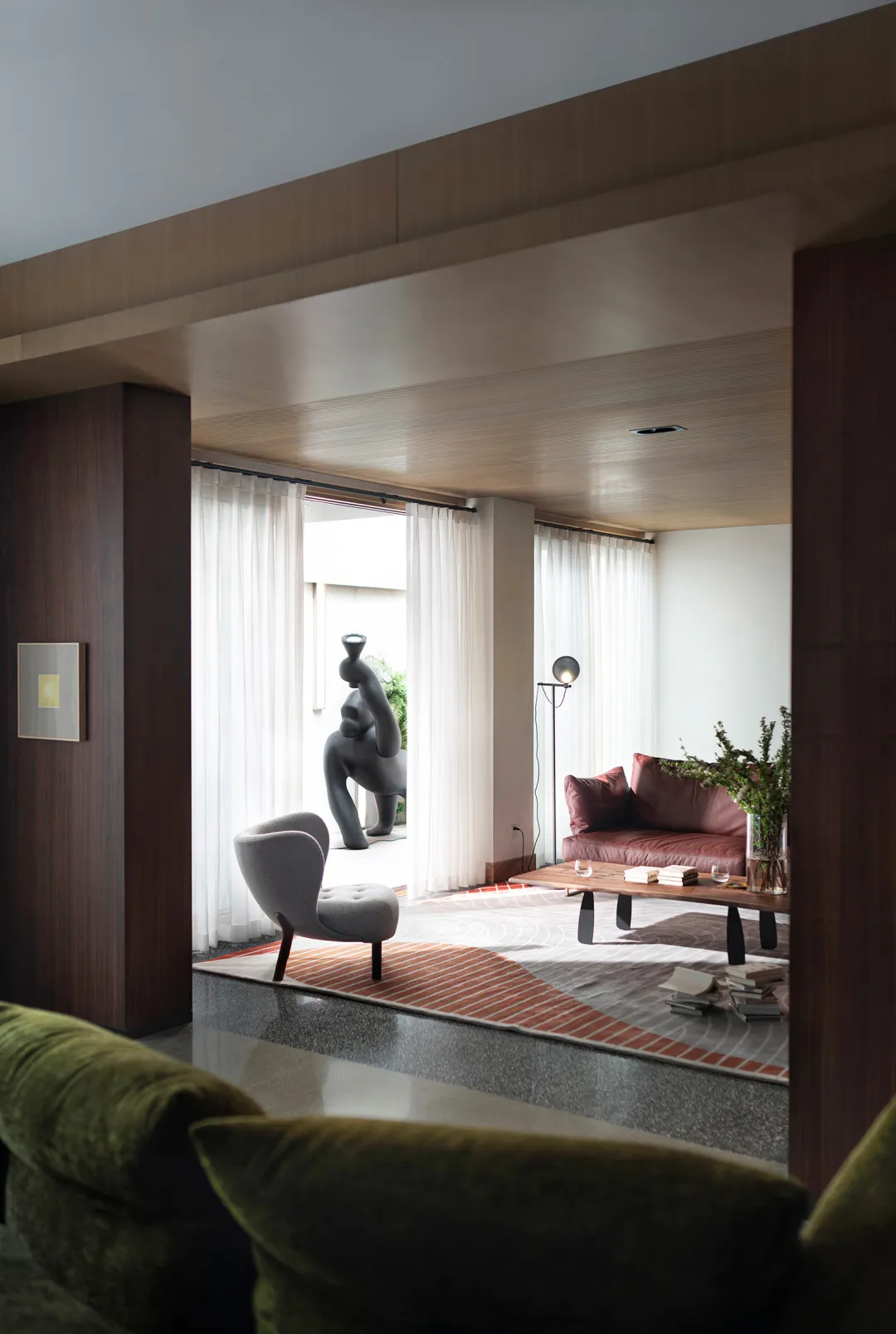 A modern living room with a wooden sofa, coffee table, and decorative elements like a vase and greenery.