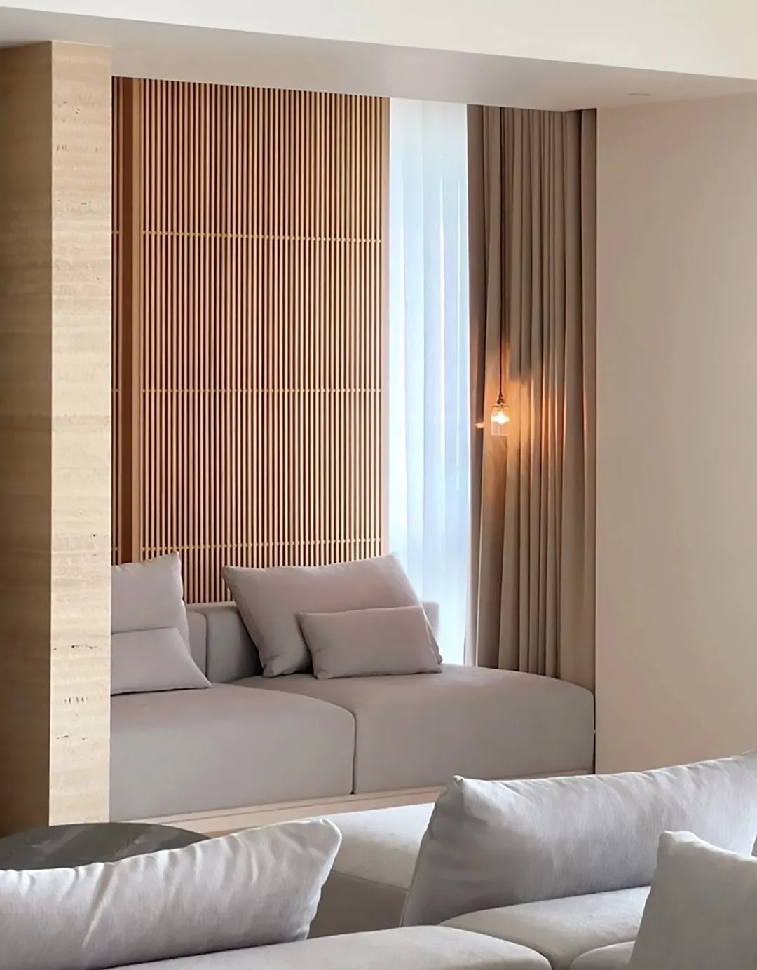 A minimalist living room featuring a wooden feature wall, upholstered seating, and soft lighting.