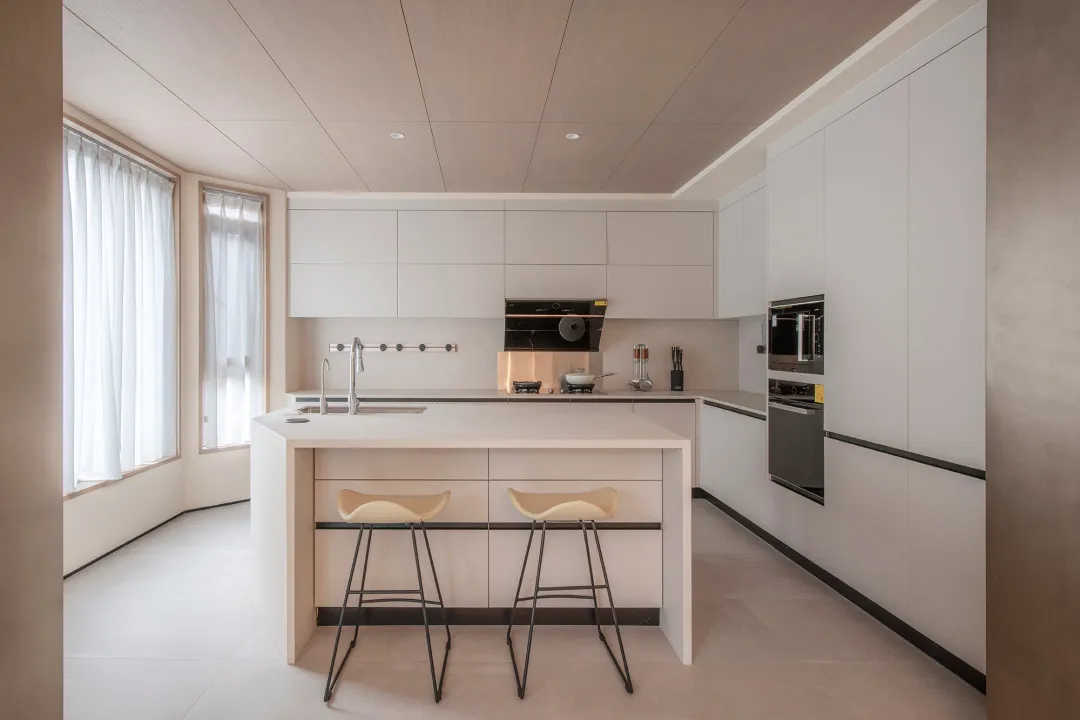 White and minimalist kitchen with a central island, modern appliances, and a sleek design.