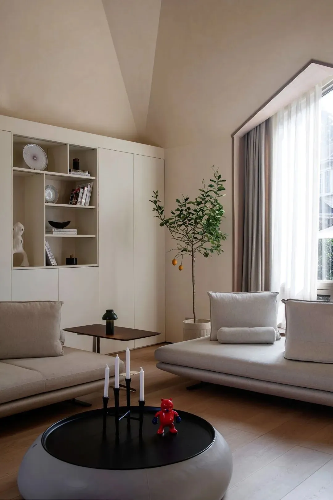 A minimalist living room with white walls, a low-profile coffee table, and a potted plant.