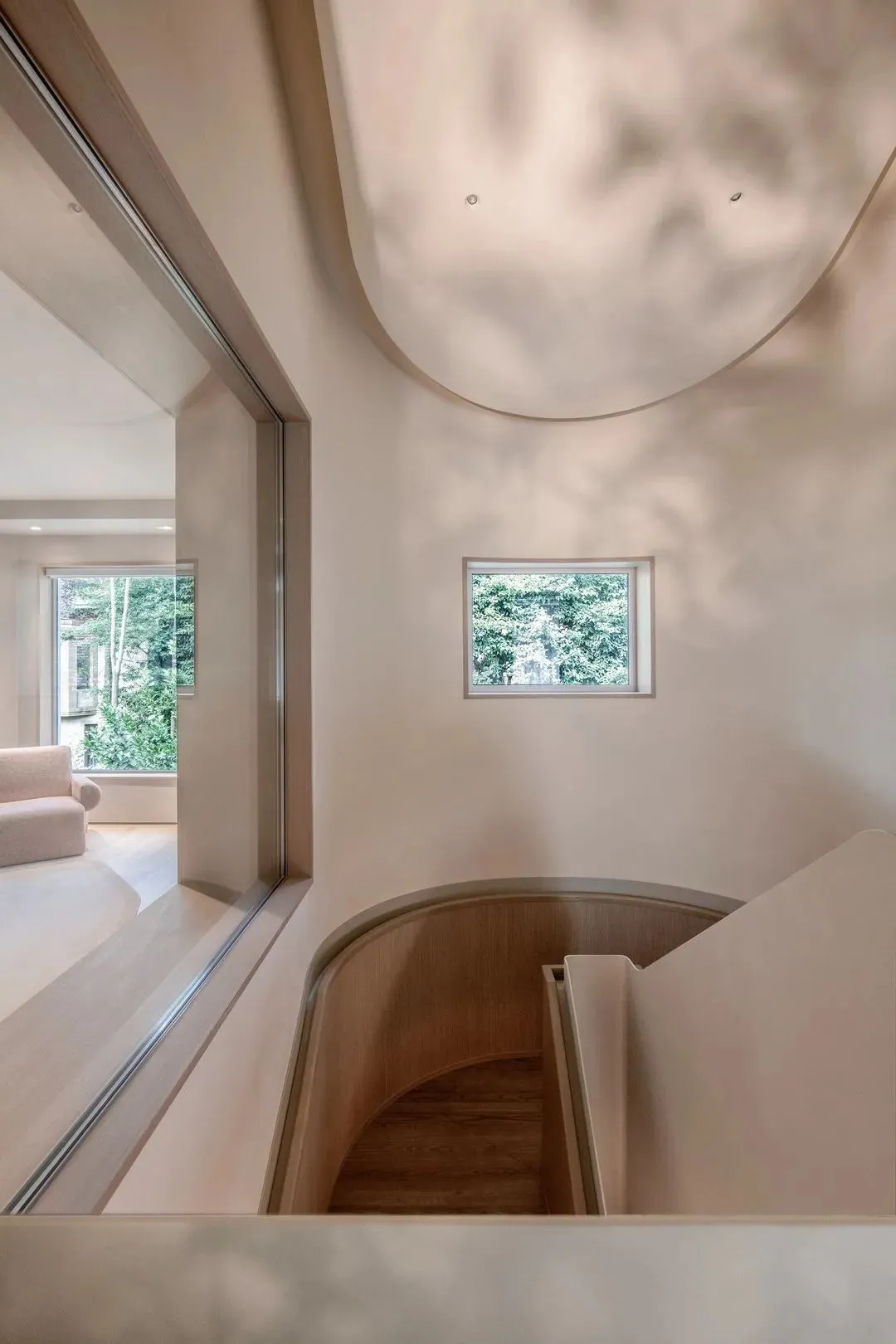 A minimalist staircase with wooden walls and floor, featuring a small window and a curved handrail.