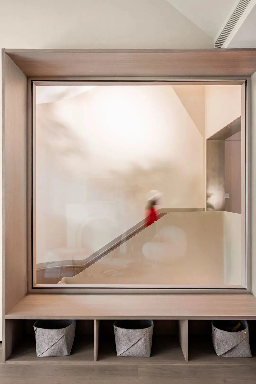 Modern minimalist staircase with glass railings and a person walking down it.