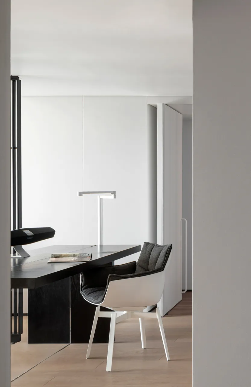 A modern, minimalist office space with a sleek black desk and contemporary chair.