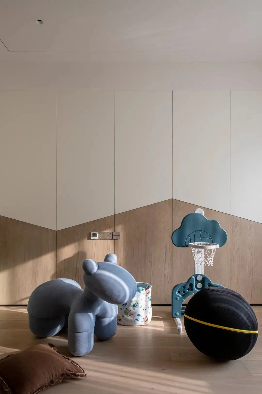 A cozy playroom with a ball court, stuffed animal, and storage bin.