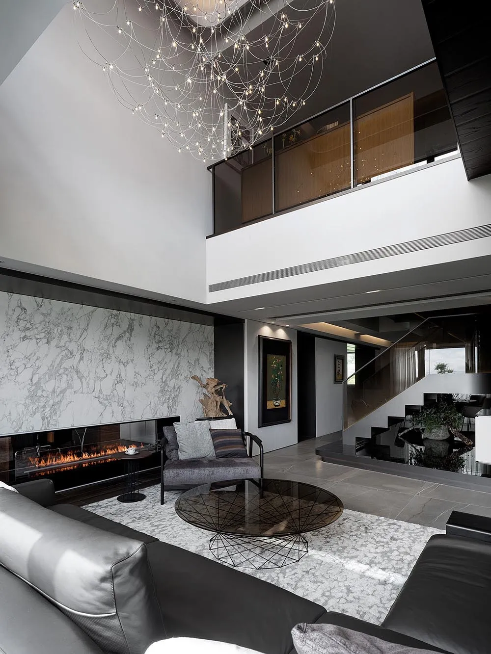 A sleek modern living room featuring marble accents, glass elements, and metal finishes.