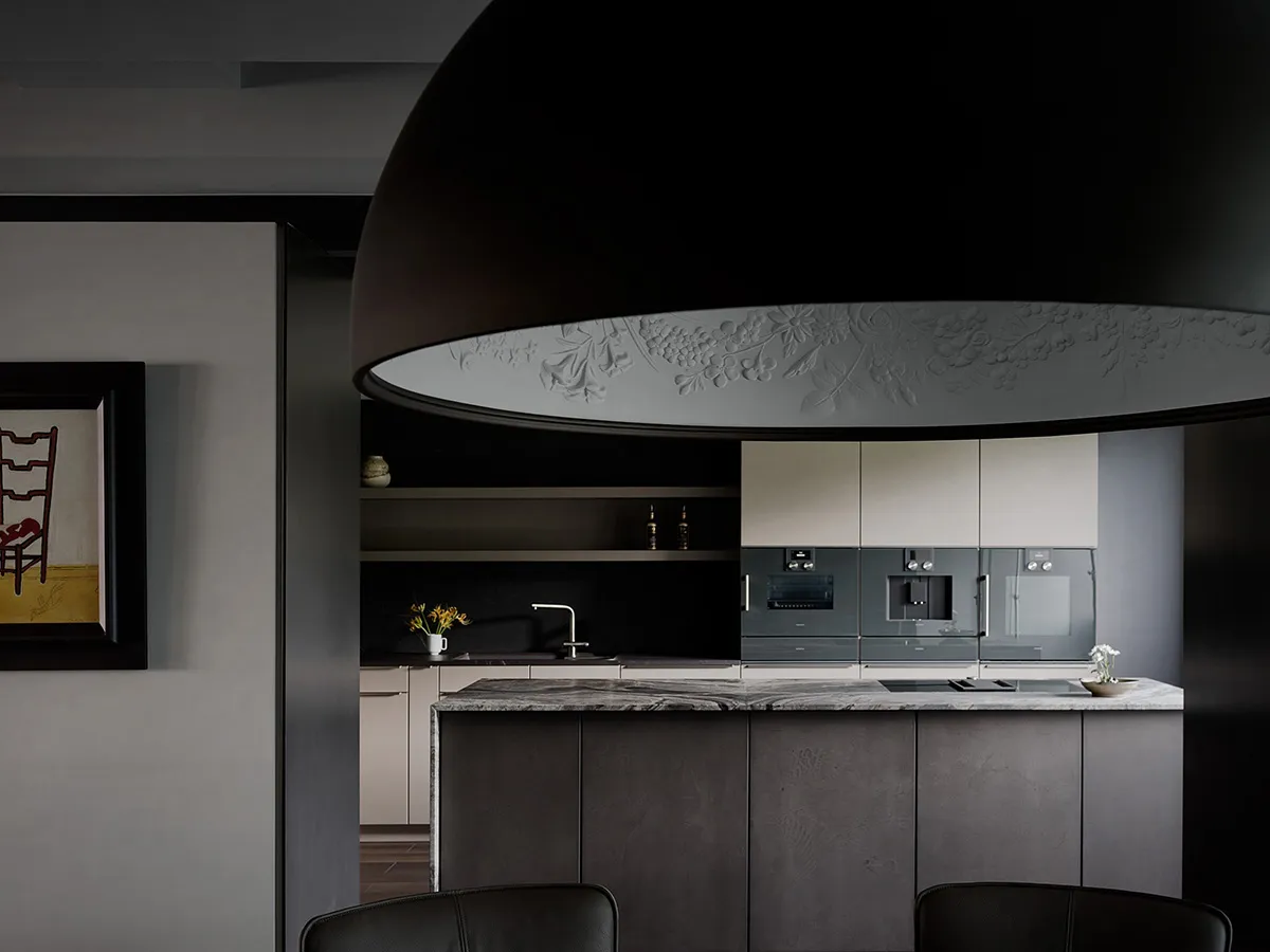 A modern kitchen with black marble countertops, minimalist cabinets, and sleek appliances.
