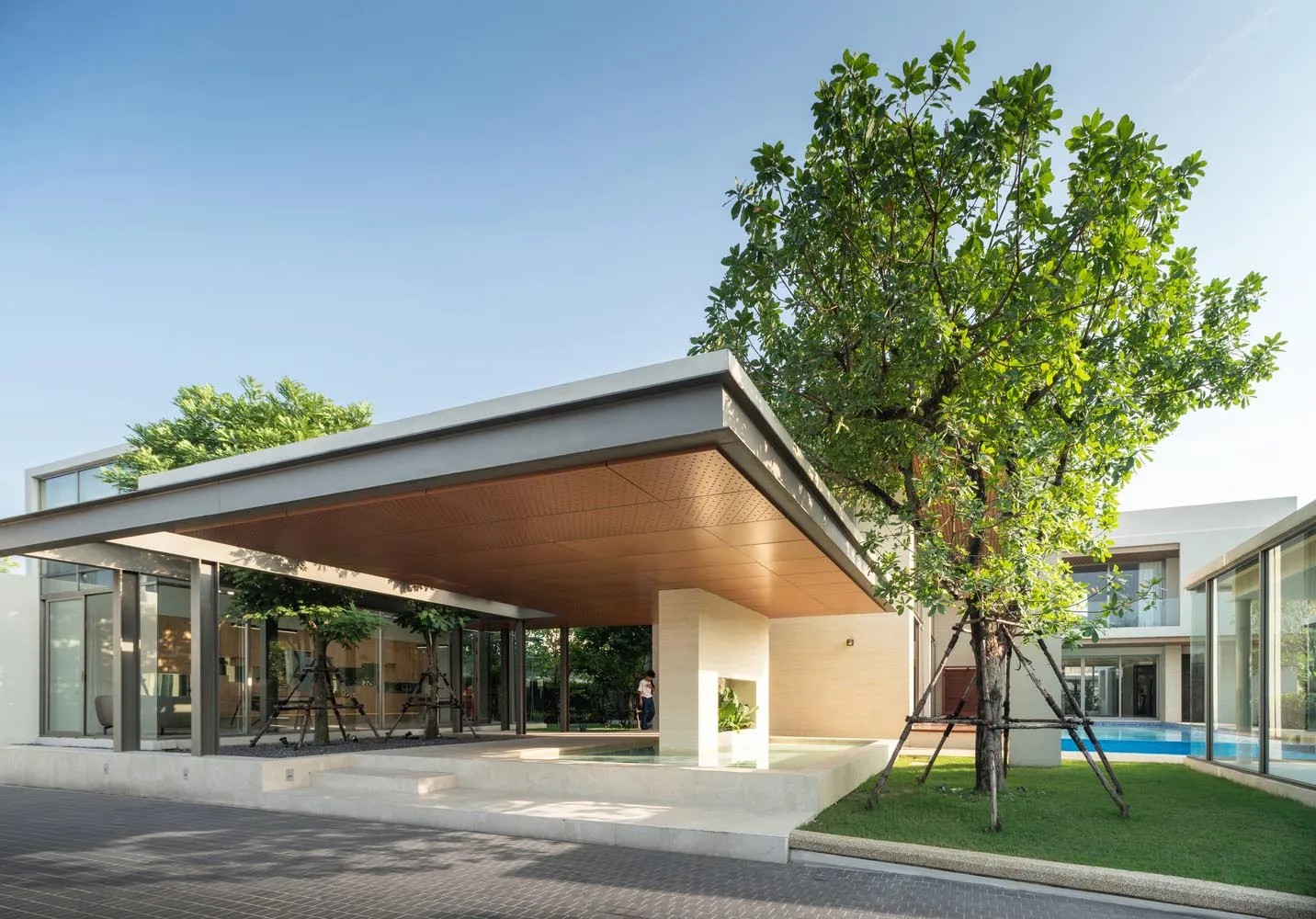 A modern residential building with a steel and glass facade, featuring a spacious outdoor patio and a swimming pool.