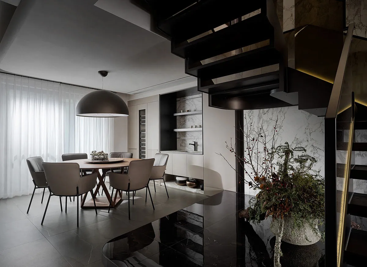 A modern dining room with marble accents, featuring a circular table surrounded by six chairs.