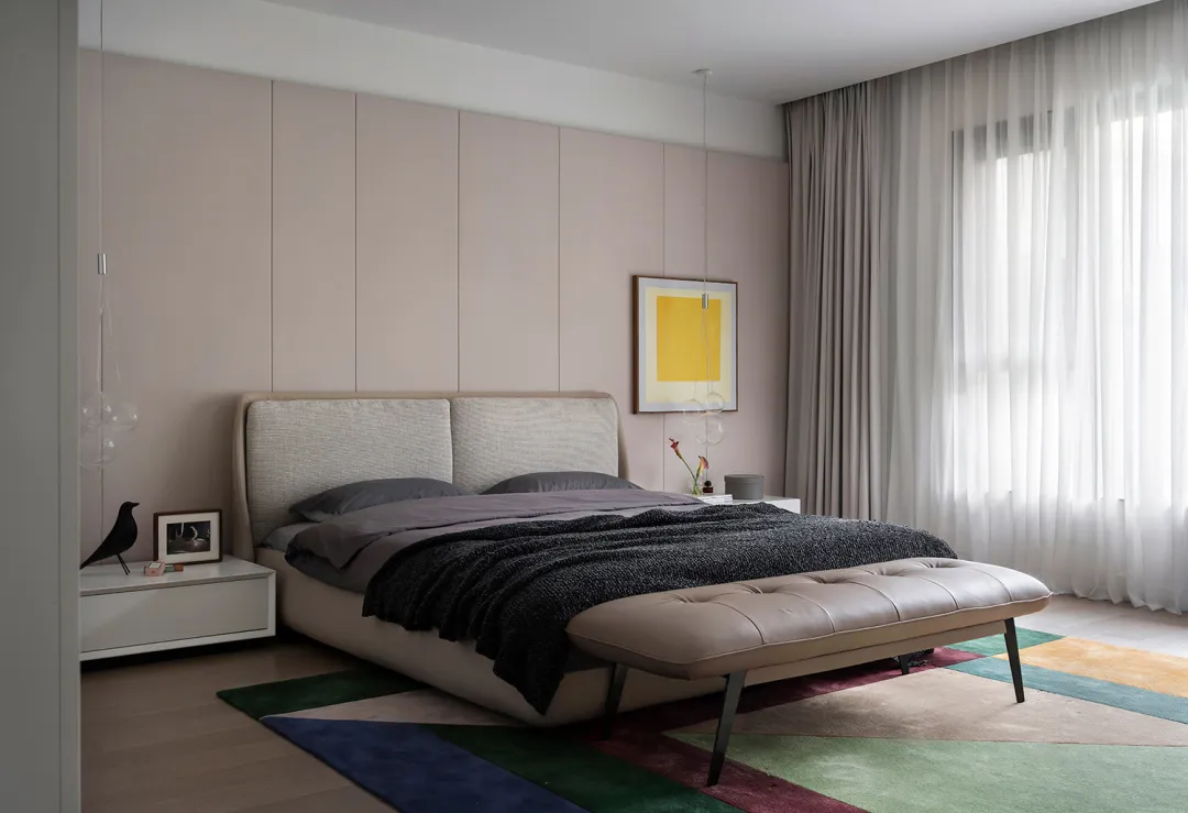 A modern minimalist bedroom with a bed, carpet, window, and artwork.
