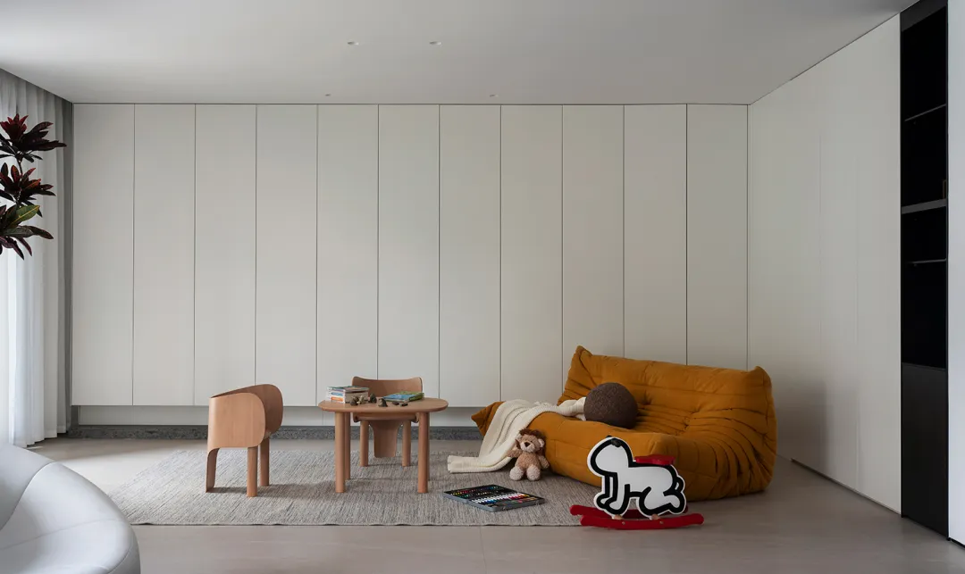 Minimalist living room with white walls, wooden furniture, leather couch, fabric toys, and modern design elements.