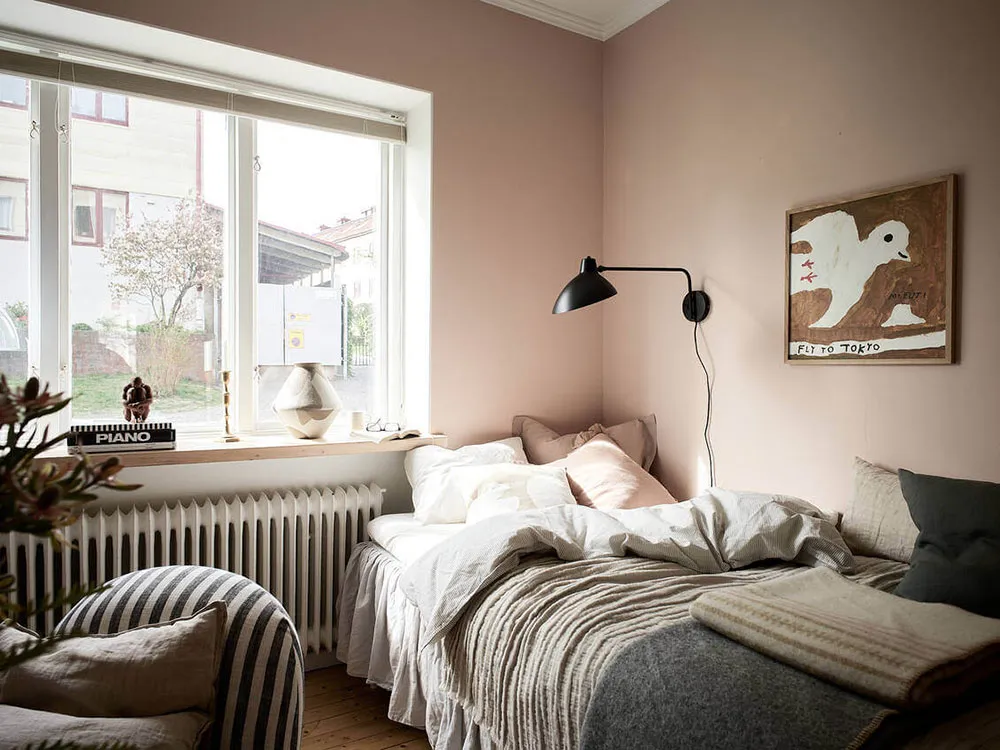 A minimalist bedroom with a bed, lamp, and artwork.