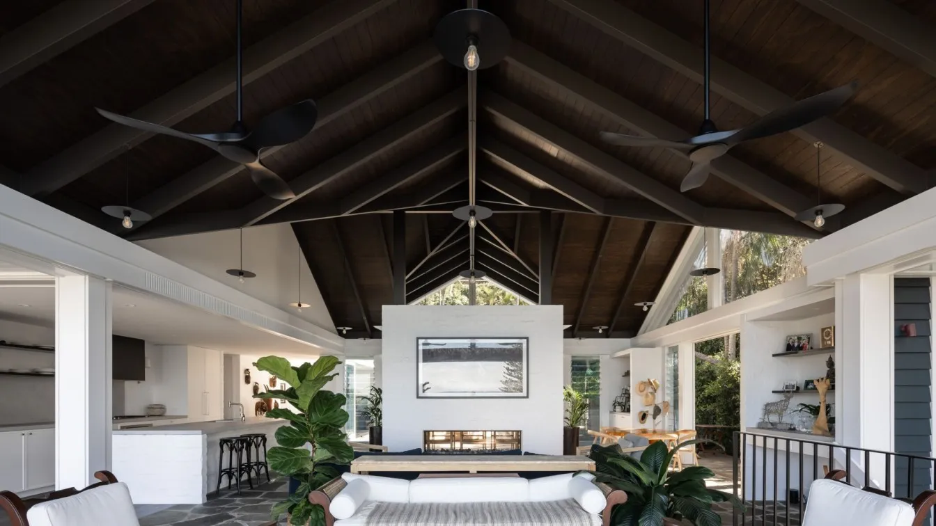 A modern living room featuring a tall ceiling, white sofa, and large windows.