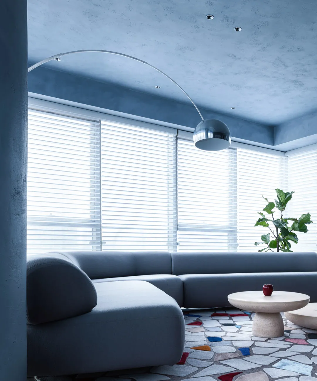 Contemporary living room interior with grey sectional sofa, glass coffee table, and modern floor lamp.