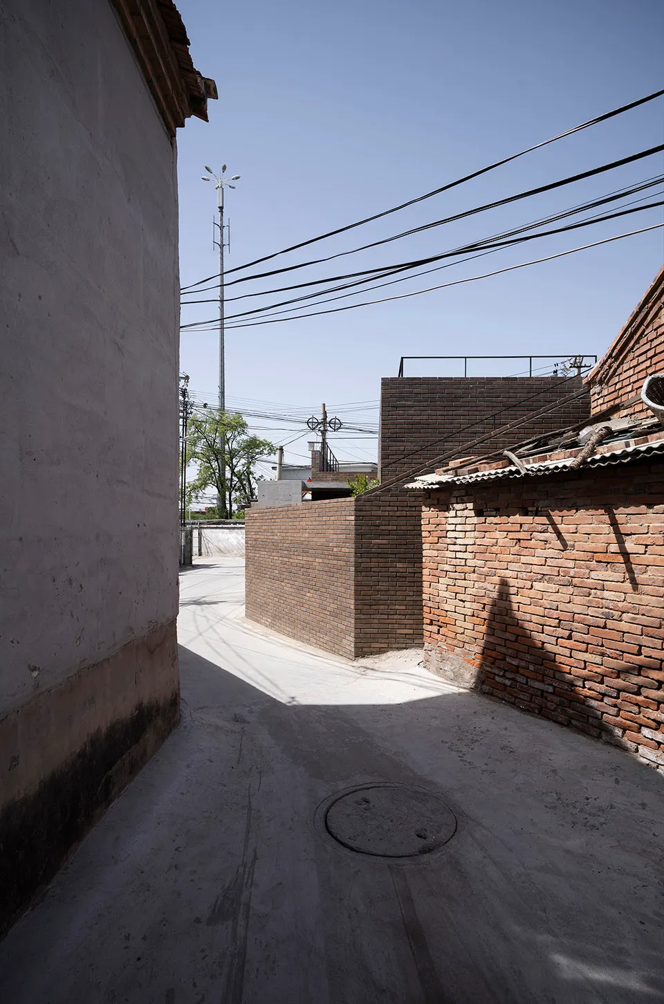 A narrow urban alley lined with brick buildings, featuring overhead power lines and a concrete pathway.
