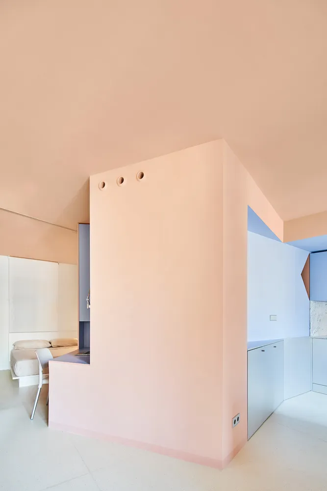 A modern minimalist residential interior with a pink wall and minimal decor.