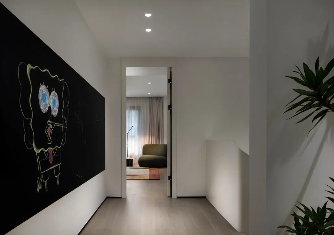 A modern home office with white walls and a blackboard on one wall, featuring a comfortable seating area and natural lighting
