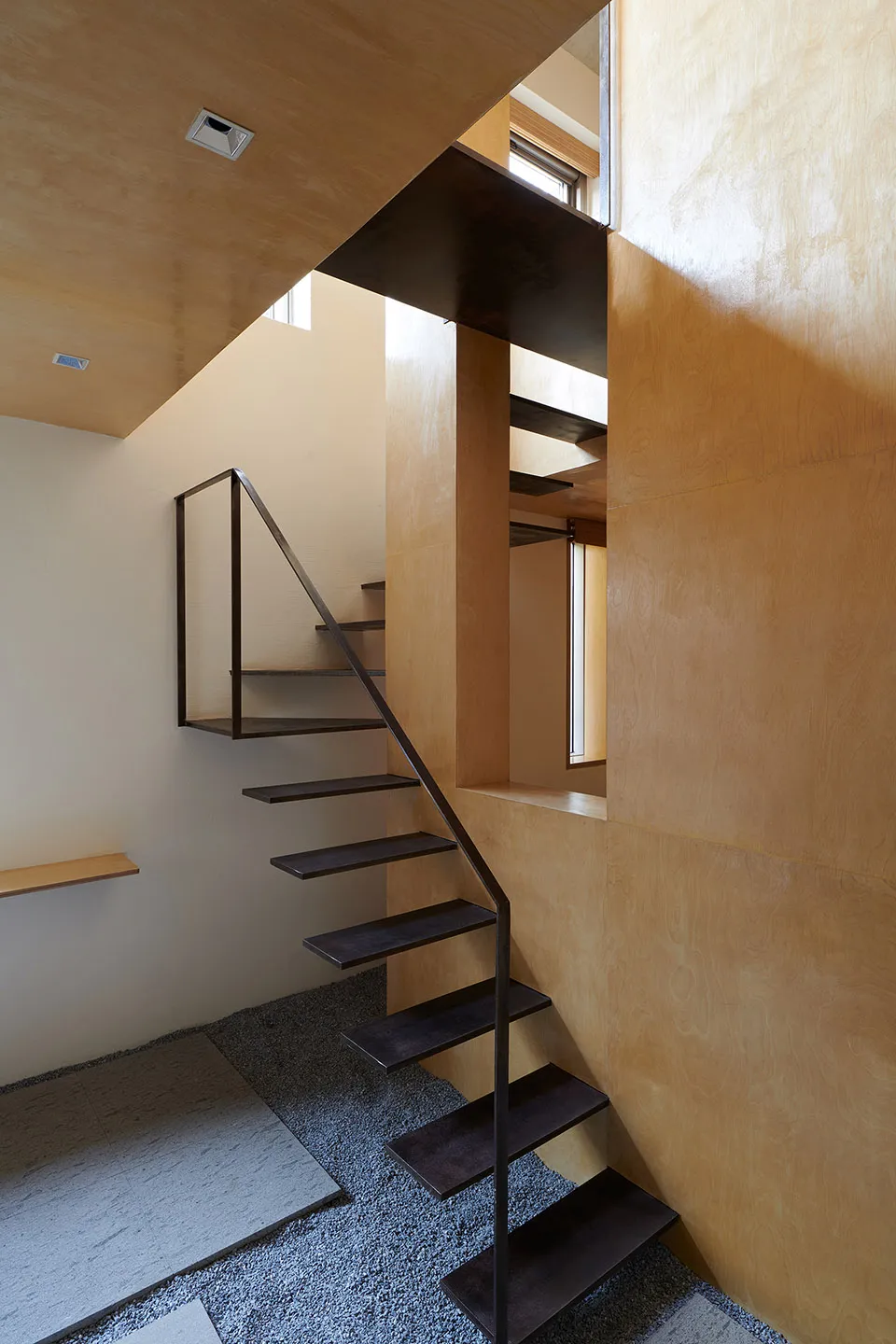 A modern industrial staircase made of metal by a wall with natural light coming in