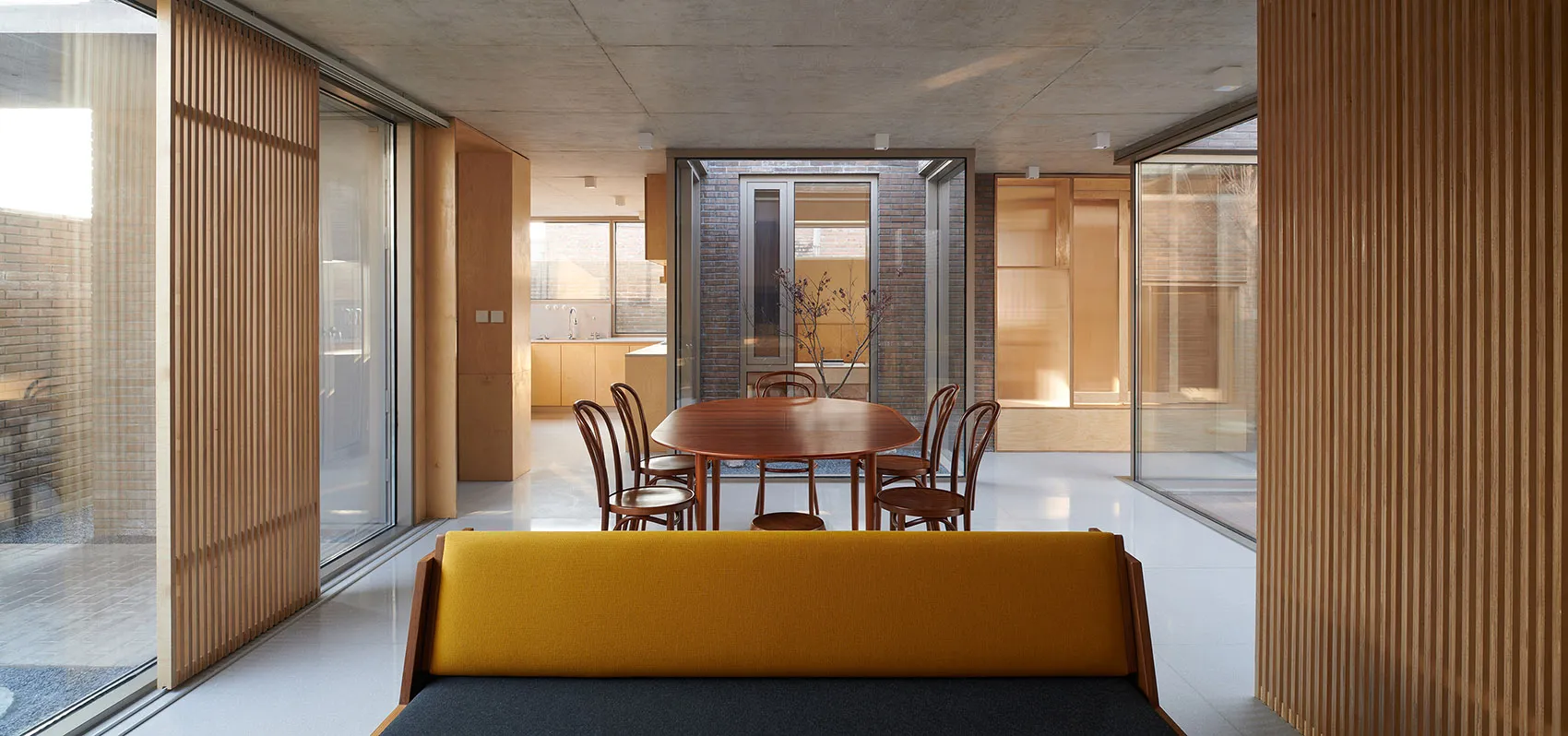 A modern residential kitchen featuring wooden furniture and white floors.