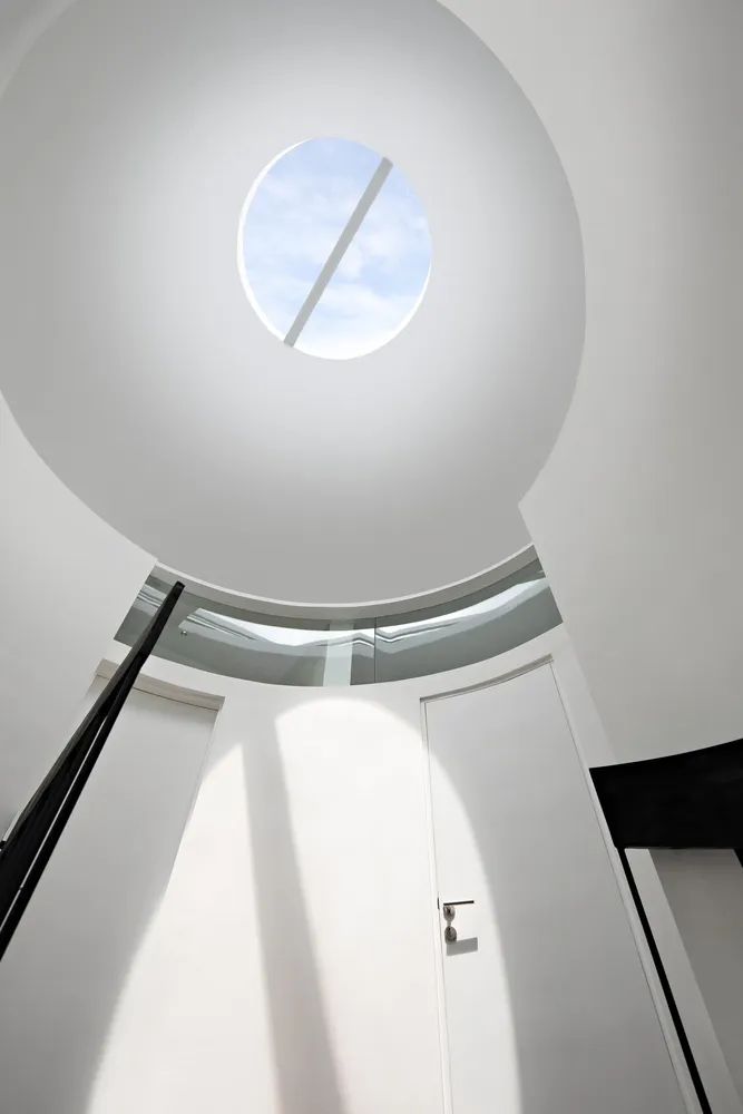 A modern white space with a glass ceiling allowing natural light to flood the area.