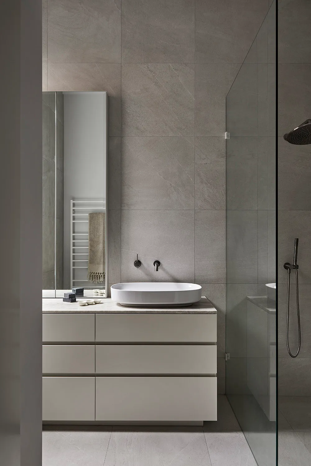 Minimalist bathroom featuring gray tile and concrete materials, showcasing sleek and modern design.