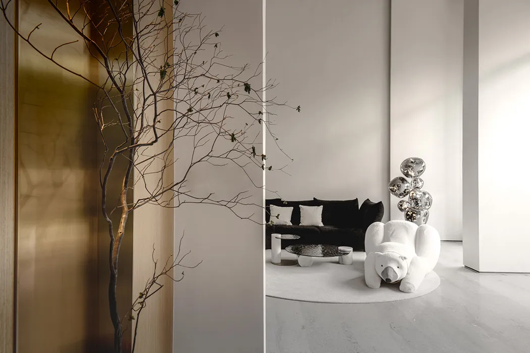 A minimalist living room with a white couch, black sofa, and a polar bear-shaped chair.