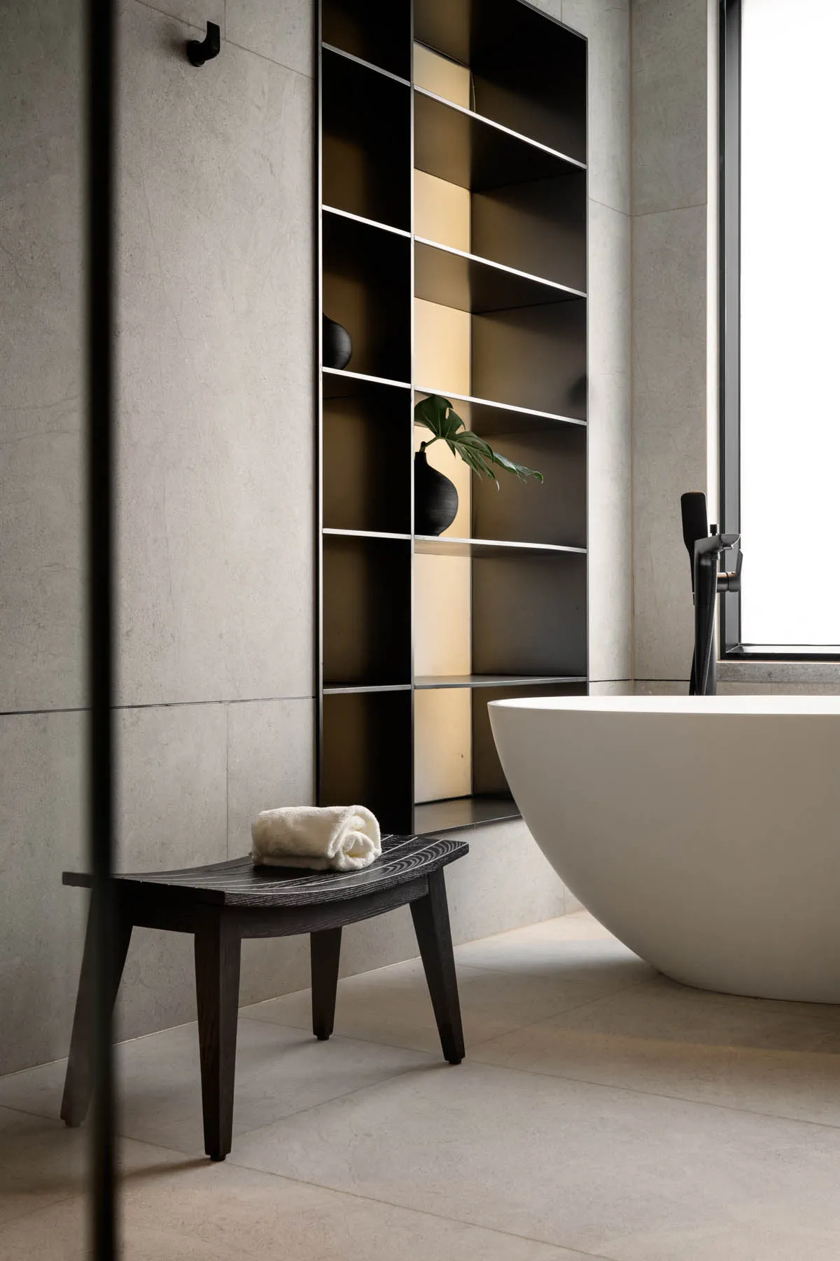 Modern bathroom interior with a concrete tile floor and wall, featuring a white freestanding bathtub and minimalist design el