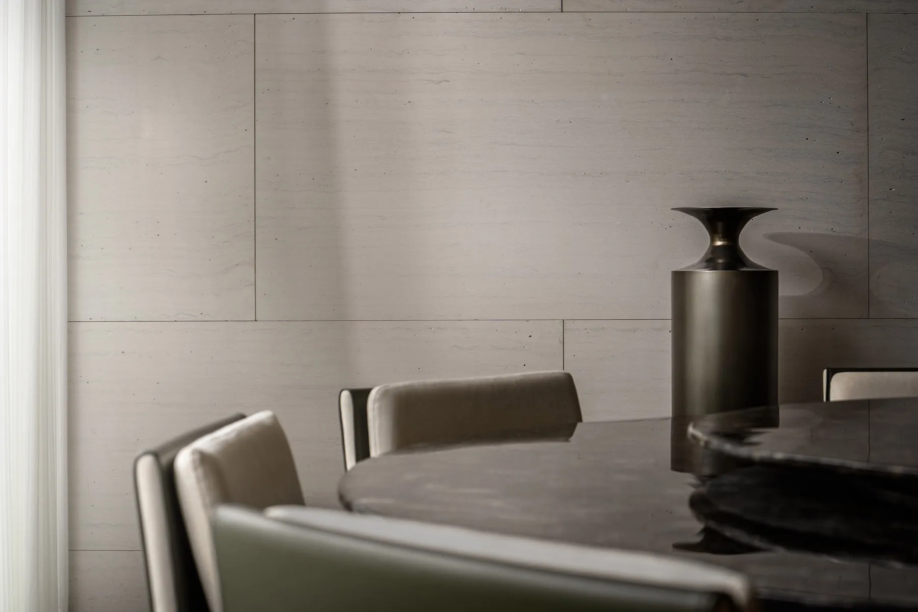 A modern dining room featuring a sleek, black marble dining table surrounded by contemporary chairs, with a minimalist aesthe
