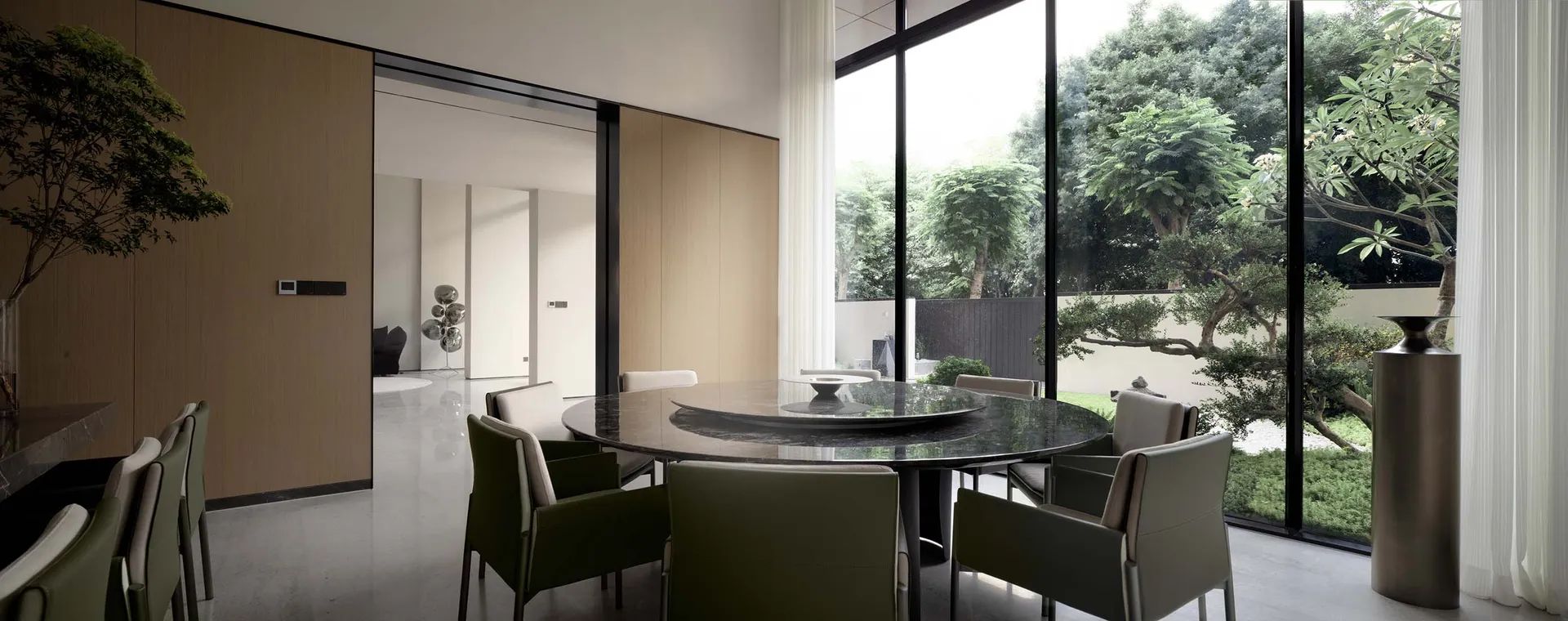 Modern dining room featuring a round marble table surrounded by chairs, with large windows providing a view of a green outdoo