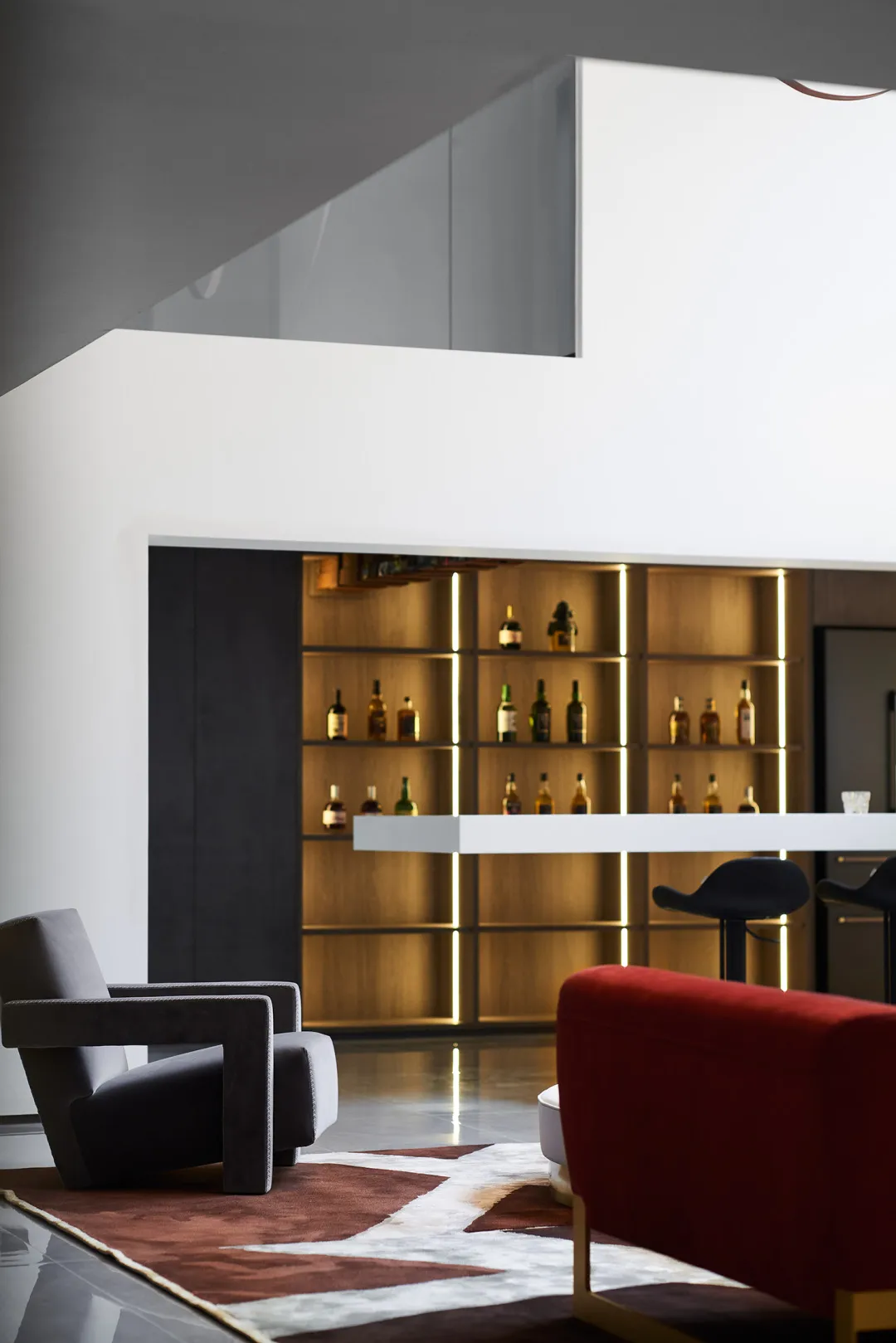 Lounge area featuring leather chairs, wooden shelves, and a bar counter.