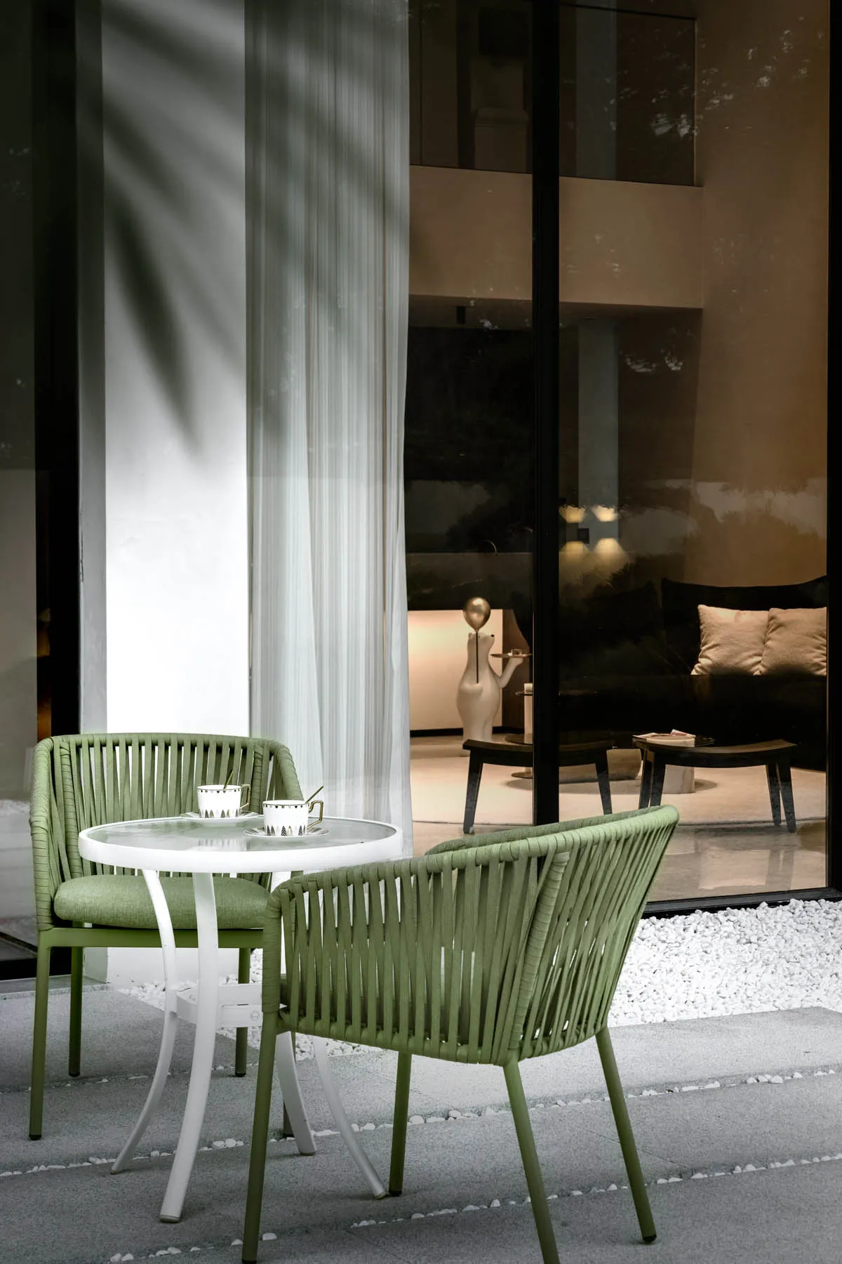 A modern, minimalist living room featuring green, woven furniture and a clean, uncluttered design.