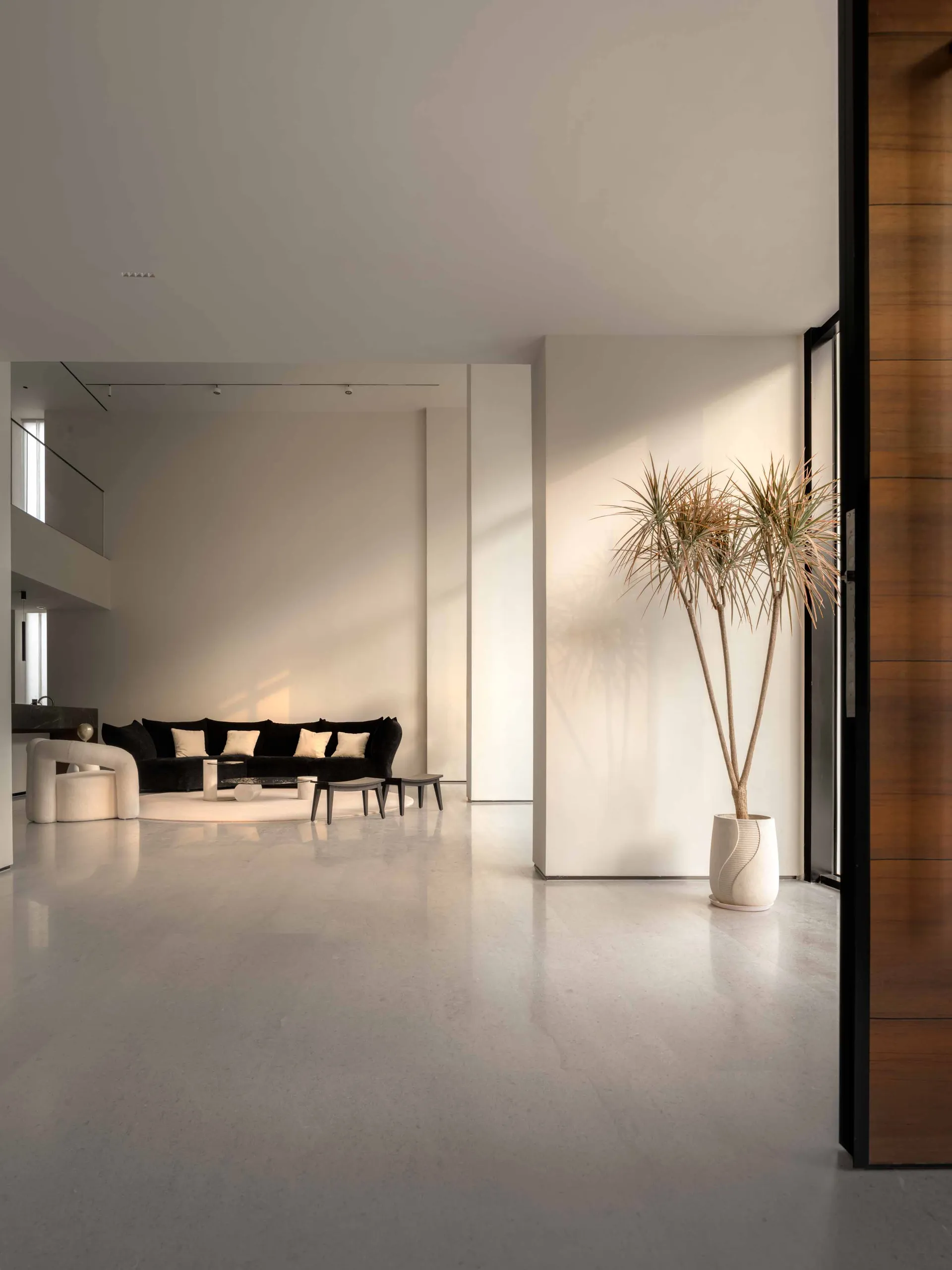 A modern, minimalist living room featuring a concrete floor, white walls, and a black and white color palette.