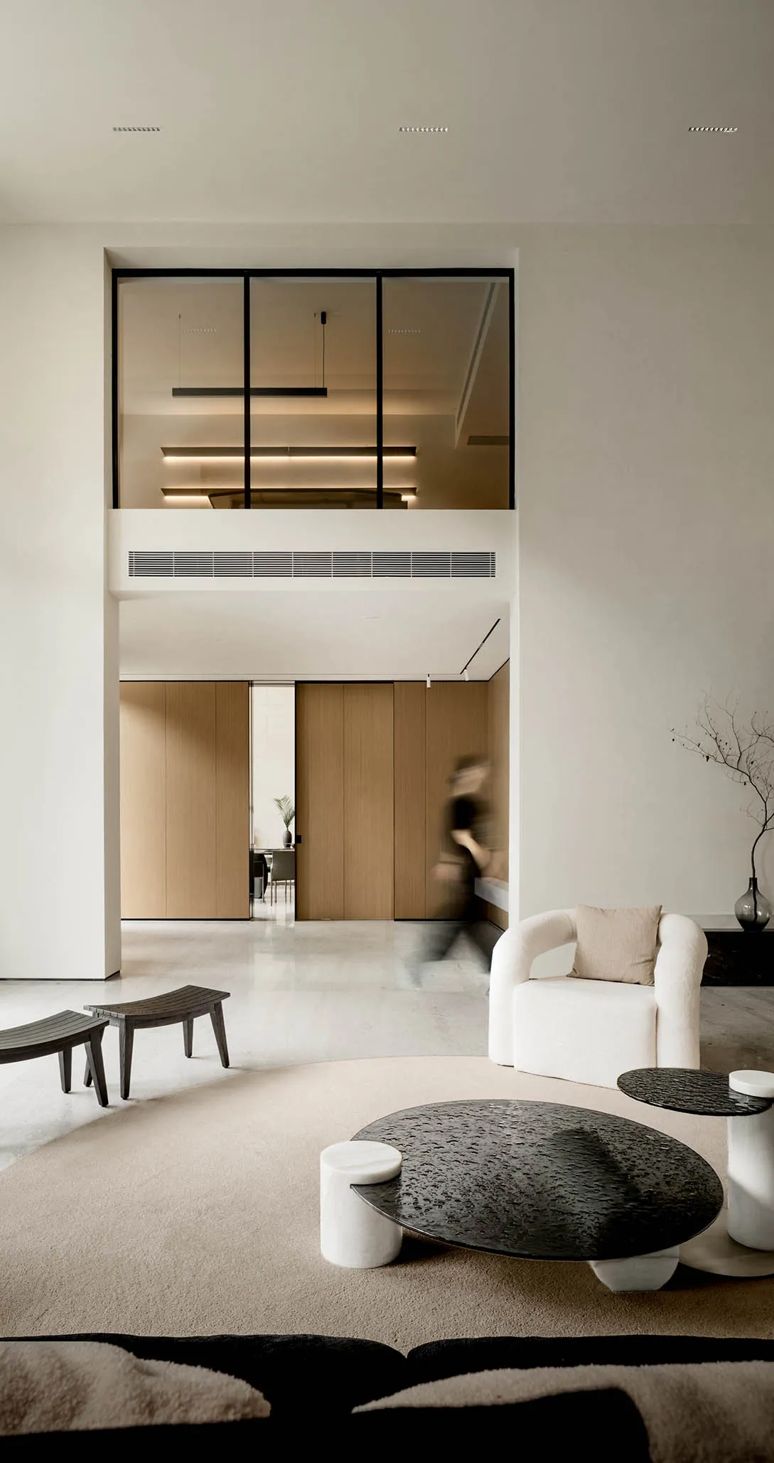 Minimalist living room with concrete flooring, white furniture, and a glass partition.
