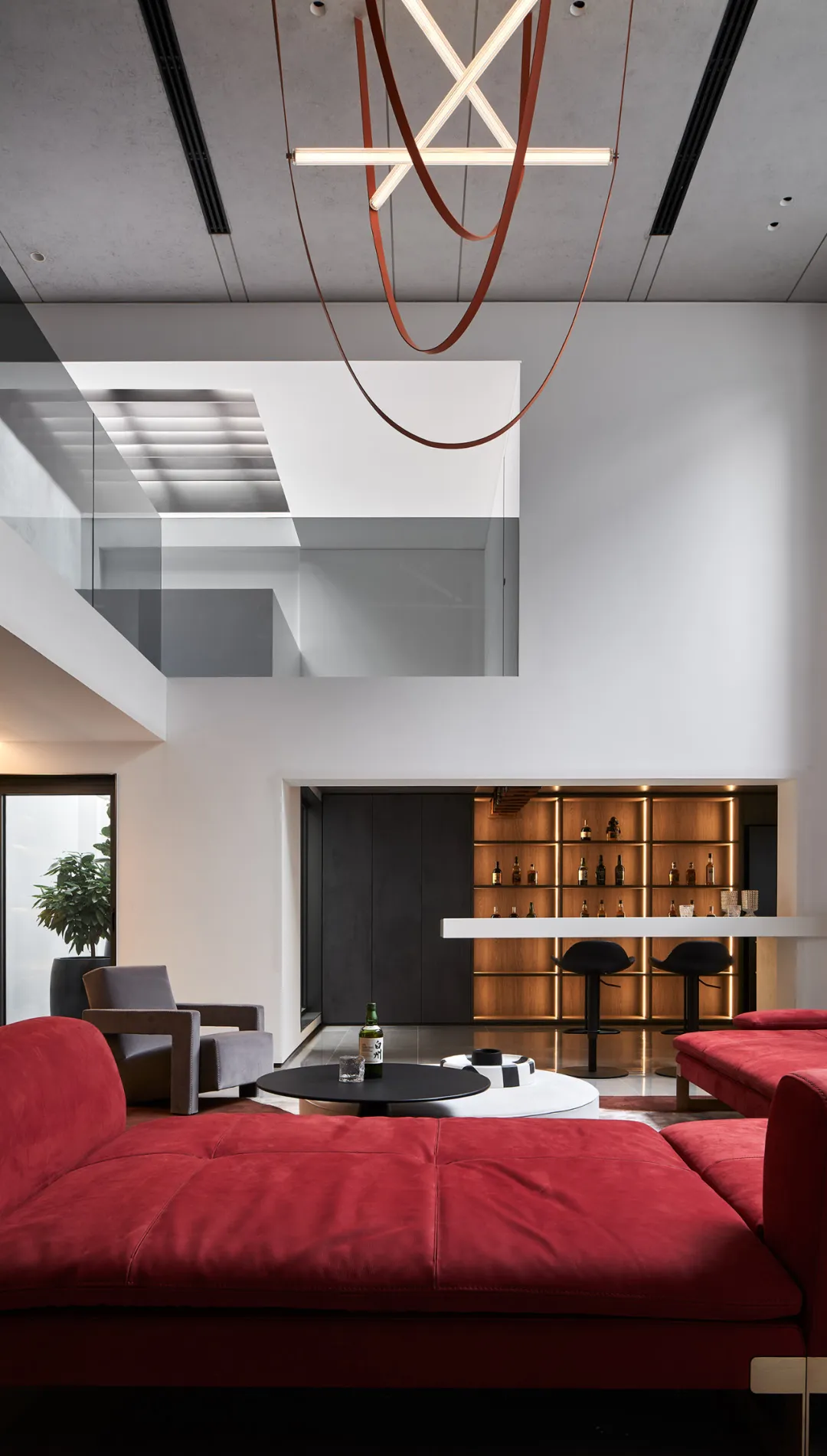 A modern reception lounge bar area with red sofas, bar stools, and a well-stocked bar.