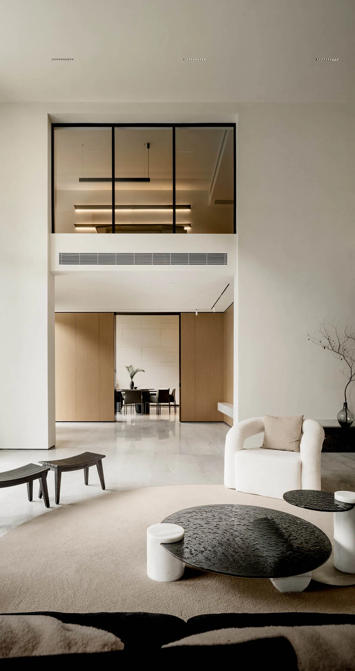 A modern minimalist living room with white furniture, black tables, and a concrete floor.