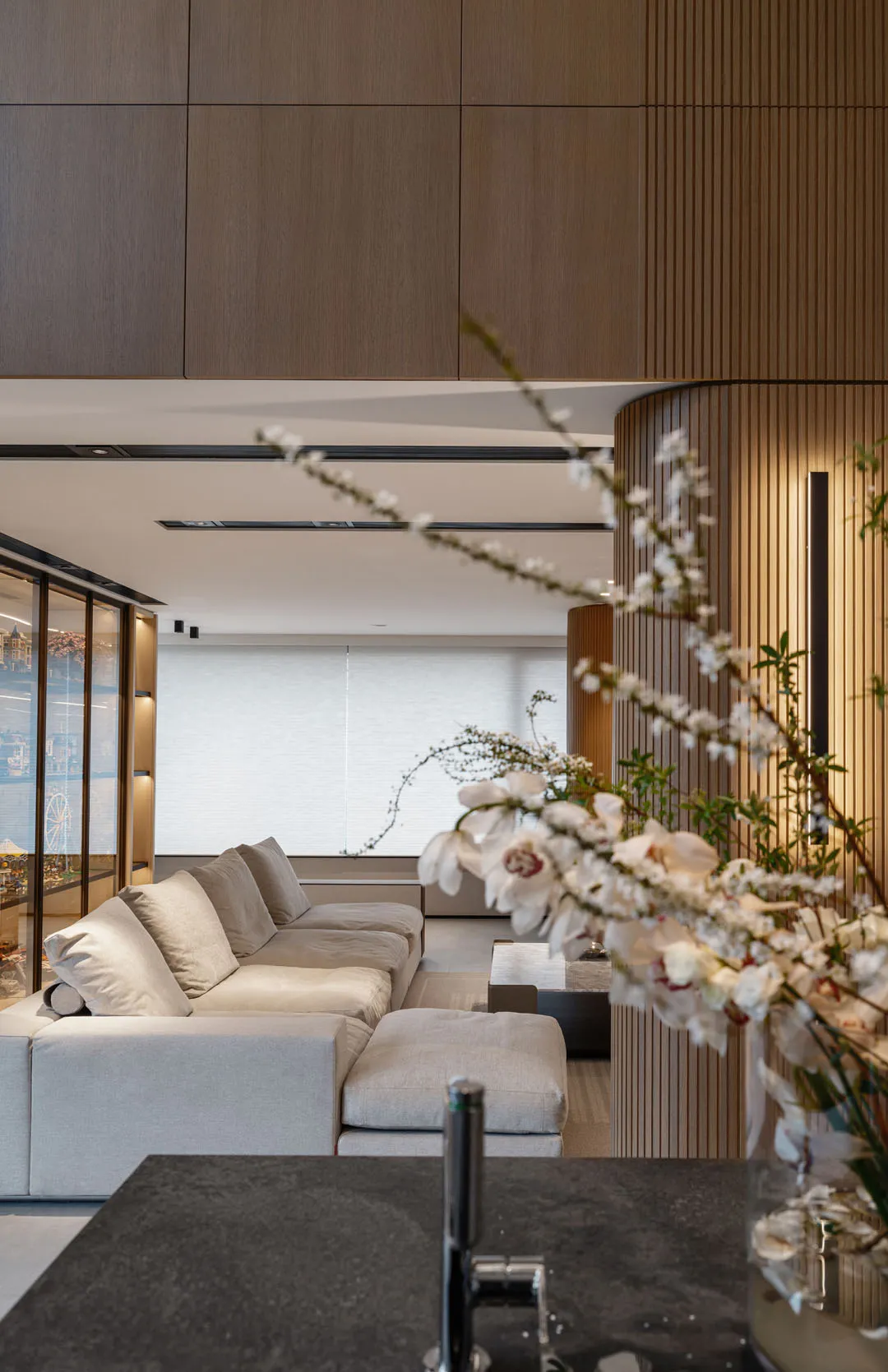 Modern living room featuring a white sectional sofa, wooden paneling, and glass windows.