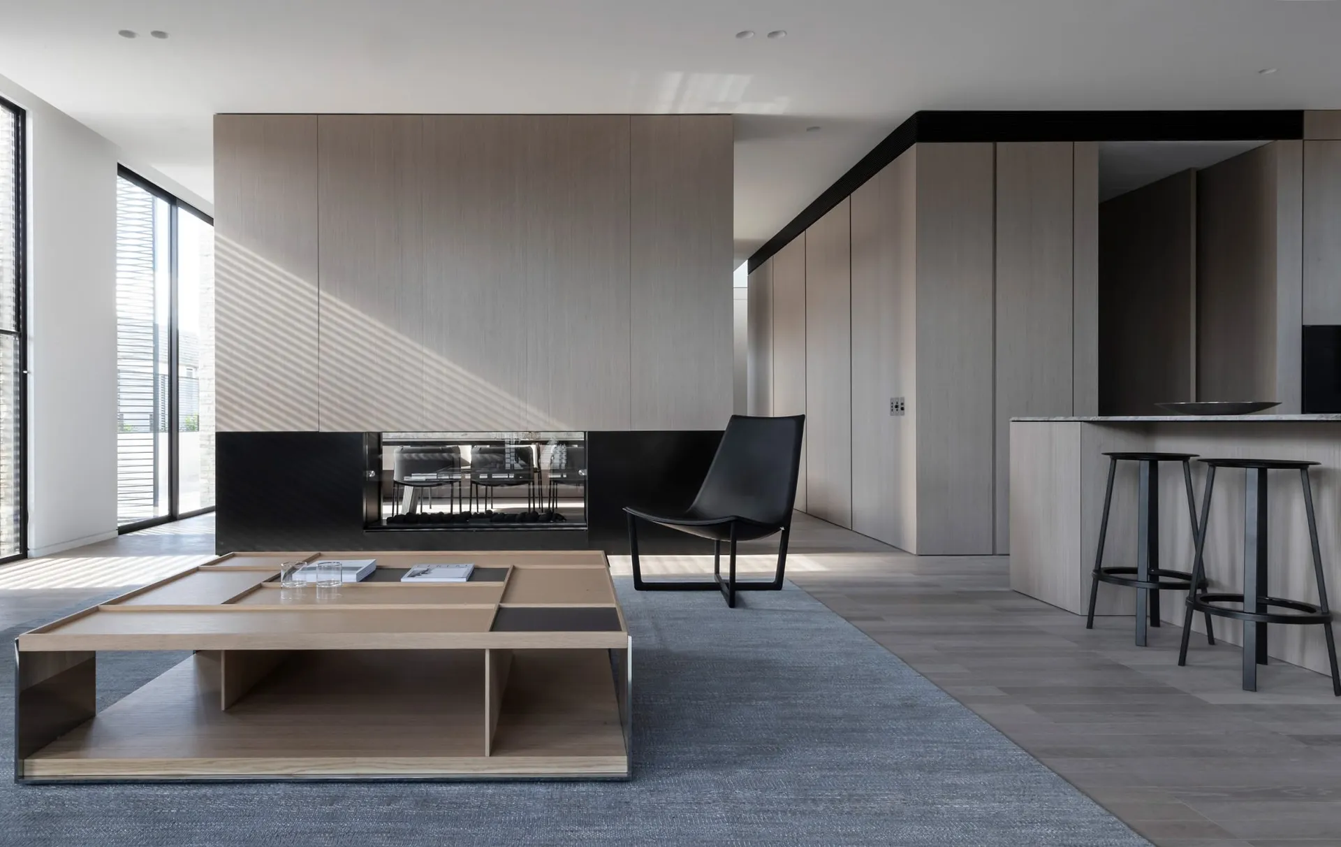 Modern living room with wood and metal furniture and black armchair.
