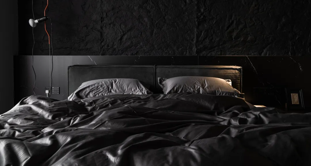 Modern minimalist bedroom with black textiles and white lighting