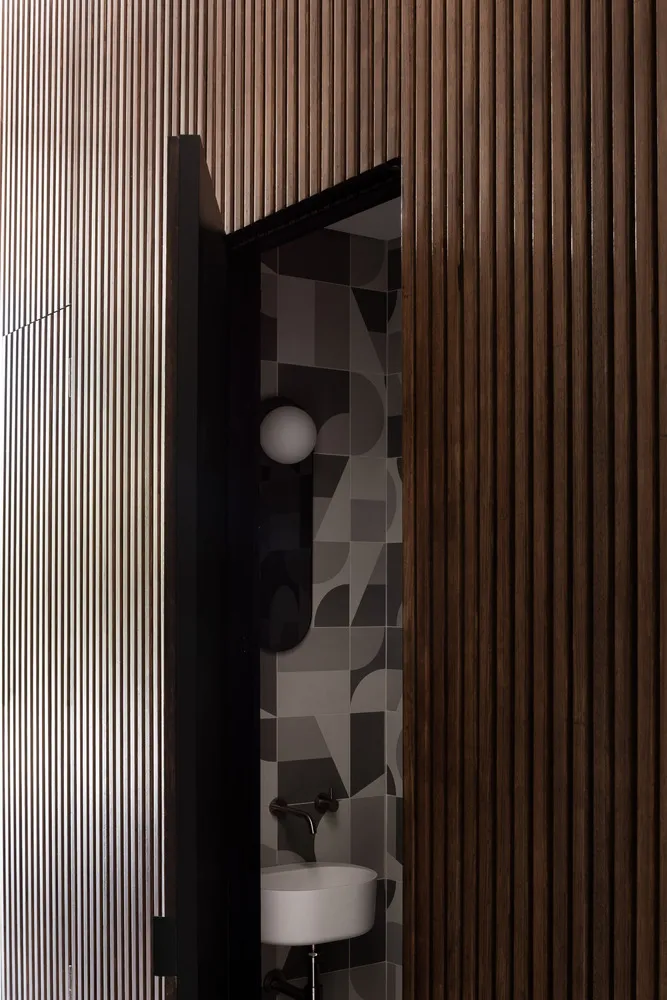 A modern bathroom with a wooden wall and geometric tiles.