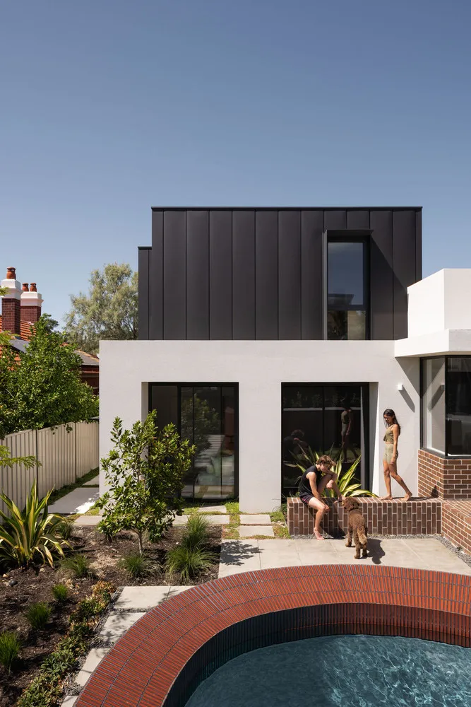 A modern residential house featuring a black concrete exterior with large windows and a swimming pool.