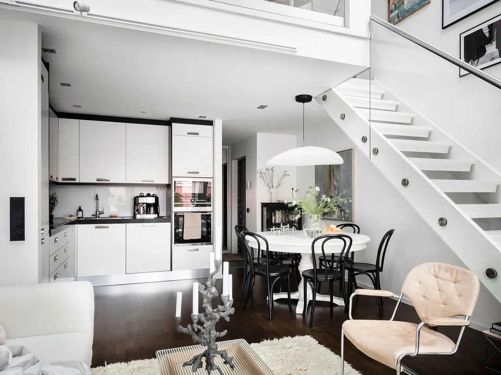 A modern kitchen and dining area featuring white furniture and white walls.